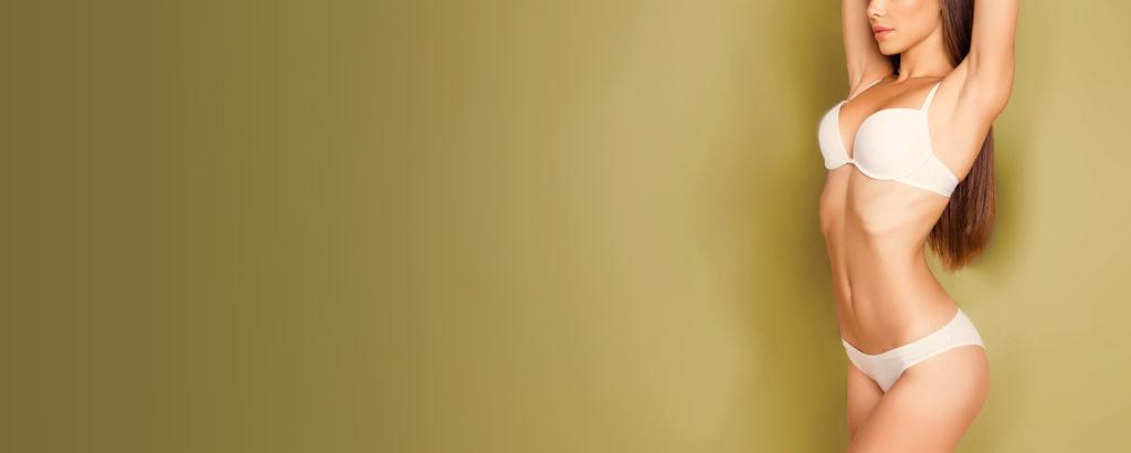 A caucasian model in a white bikini with her arms behind her head in a mustard gold room