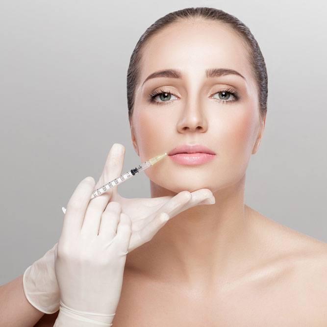 Caucasian girl getting and injectable facial surgery with a grey background