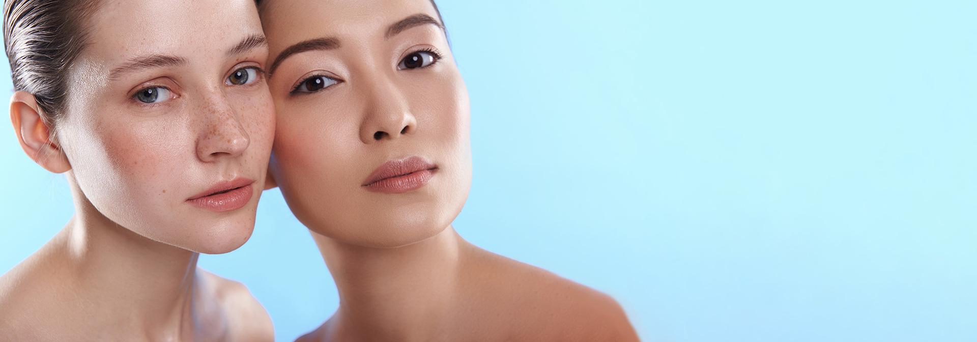 Caucasian and asian girls standing infront of a blue gradient backgroundWhite