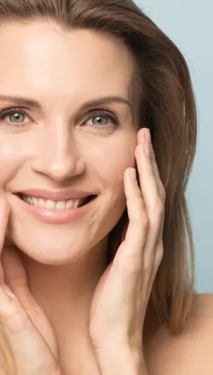 Skin Care: a middle aged woman with clear skin is smiling with her hands on her cheeks