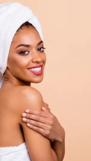 Skin Rejuvenation: A young African-American woman in a bath towel is smiling at the camera