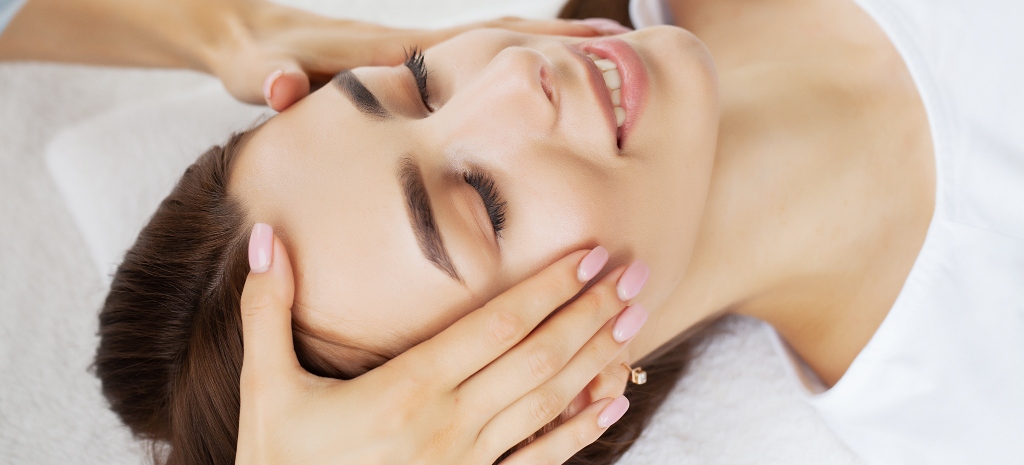Young woman enjoying of facial massage in spa salon after facelift.