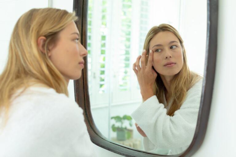 Woman looking in mirror at her eyes.