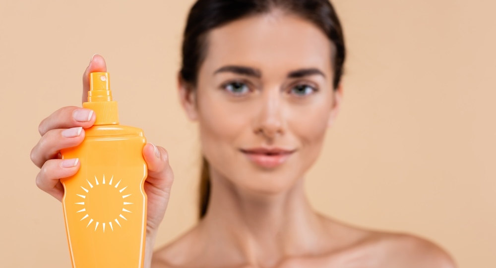 Blurred woman holding spray bottle of sunblock