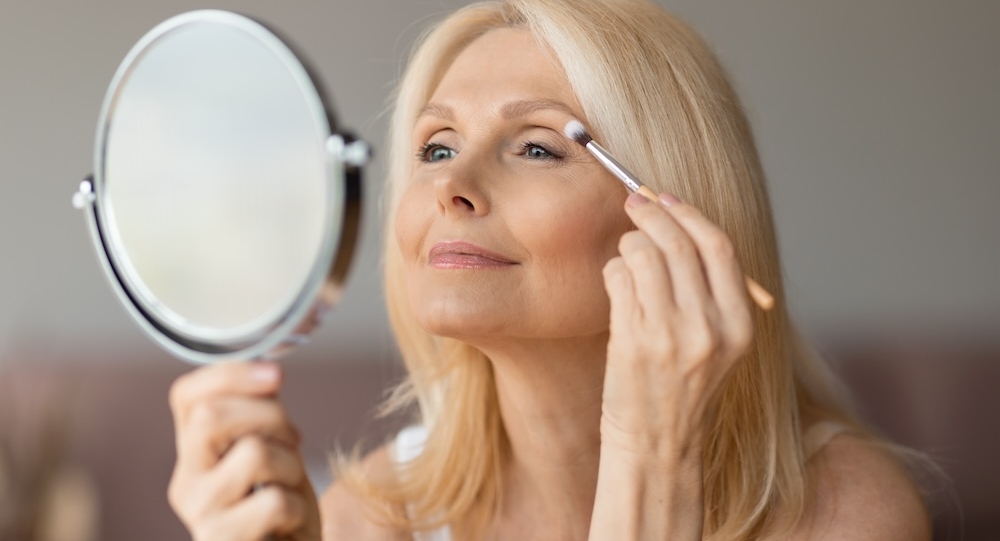 Senior woman applying eye makeup