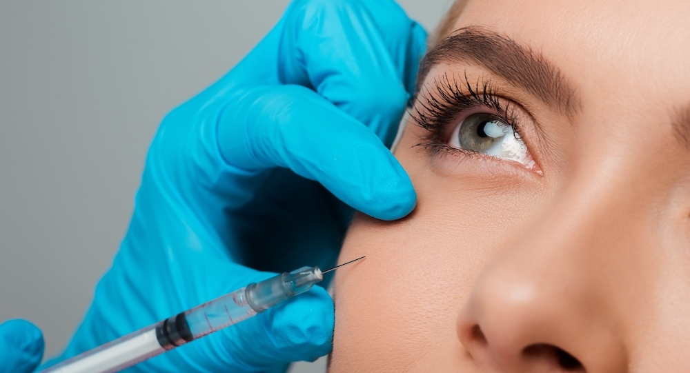 Beautician administering dermal fillers beneath eye area