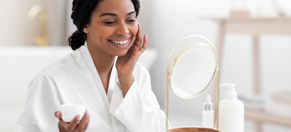Woman putting on skincare products and smiling