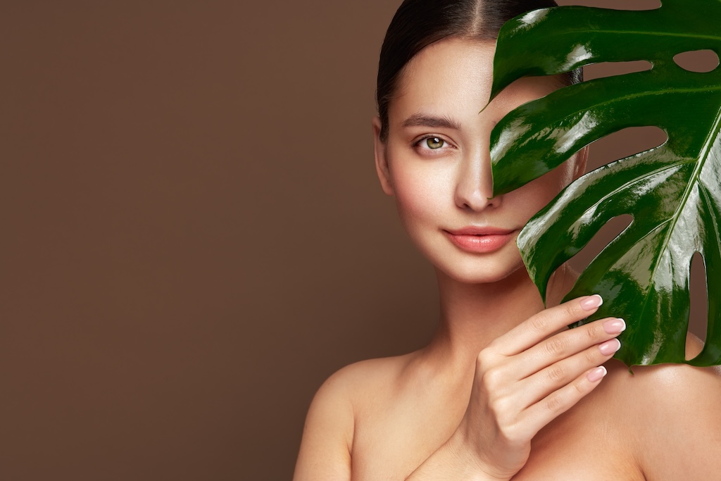 Close up woman face with green exotic leaf.