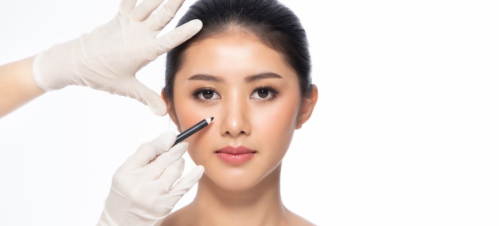 Lines on face, close up, plastic surgery concept, doctor's hand in glove making marks on patient's face.