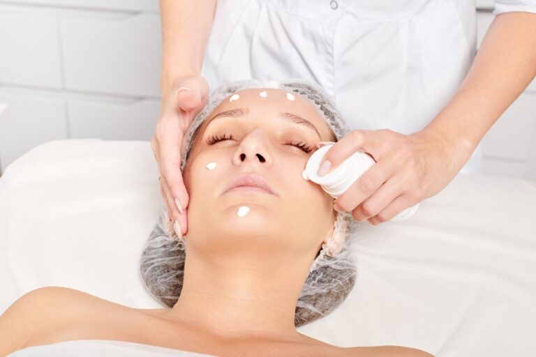 Beautician applying moisturizing cream on woman face for rejuvenation face skin, rehydration cosmetic procedure in spa salon. Professional cosmetologist applying revitalizing cream mask for skincare